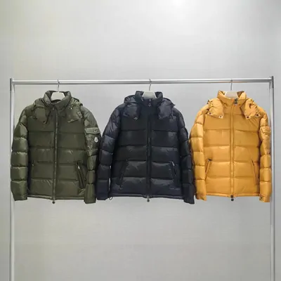 Three hooded puffer jackets in olive, navy and mustard on a clothes rail